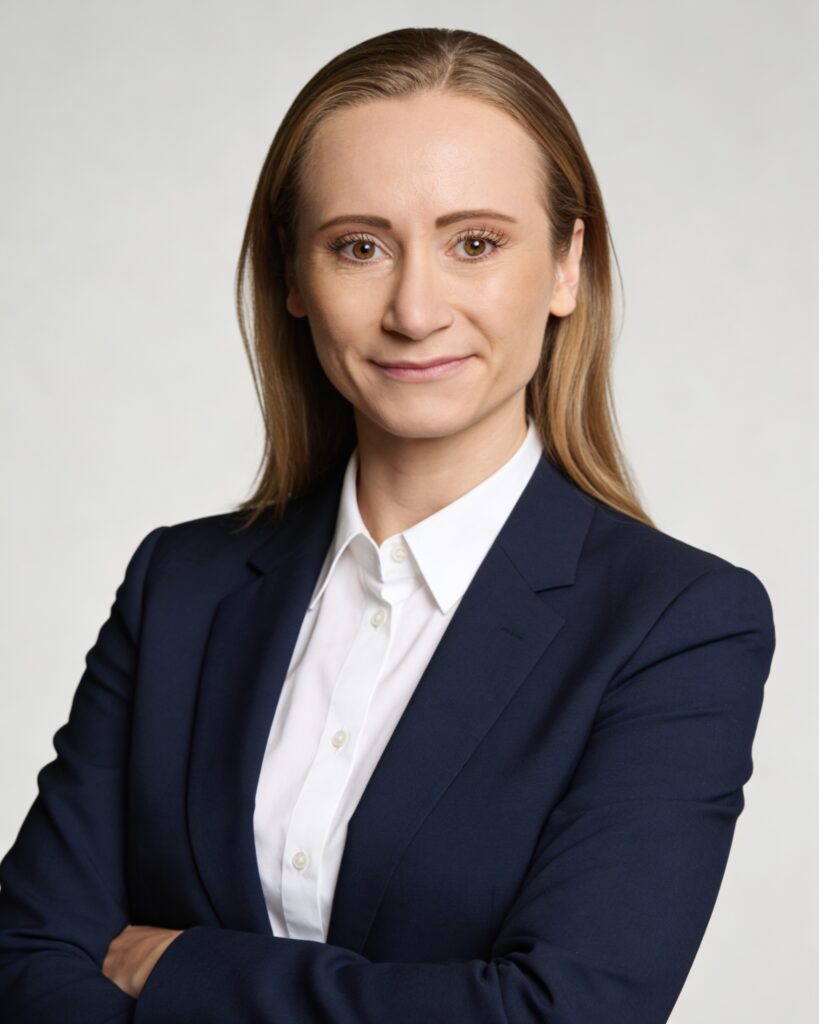 Professional woman in a navy blazer with a white shirt, arms crossed, facing the camera.